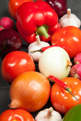 Vegetables. Peppers, tomatoes, garlic, eggplant, onions and radishes on a black background