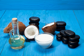 Coconut oil and stones for a massage on a blue wooden background