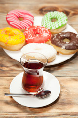 Colorful donuts and two cups of tea on a wooden table