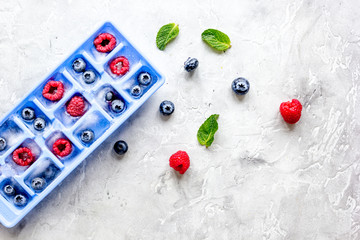 blueberry and raspberry in icetray on stone background top view mock-up
