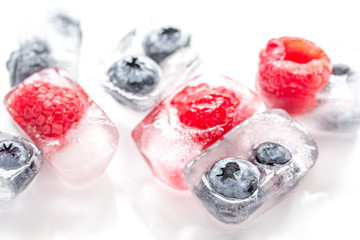 Icecubes with frozen berries on white background