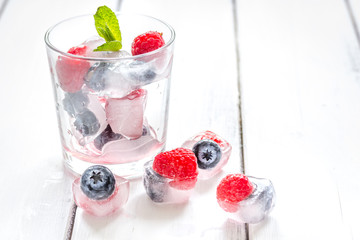 Frozen berries in glass for cocktail on wooden table background