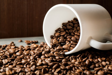 White ceramic mug with coffee beans on wooden table