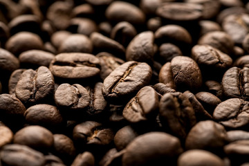 Brown coffee beans closeup macro shot, dark light.