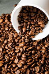 White ceramic mug with coffee beans on wooden table, vertical sot