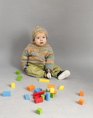 Small boy with his toys scattered around him on wooden floor