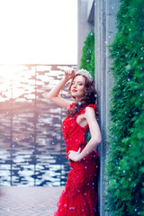 Snow Queen in red. Winter woman in crown in a red dress and red lipstick. Girl with snowflakes