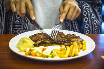 Girl eating a steak in a restaurant.