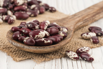 Beans in a wooden spoon on old wooden table.