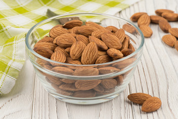 Almonds in a glass bowl on the old wooden table.
