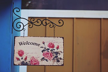Welcome sign hanging with wooden vintage background