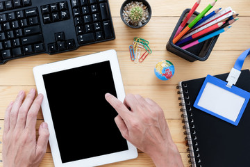 Bussinessman hand holding blank screen tablet on wooden desk table.Working thinking concept.Top view.Business analysis and strategy concept.