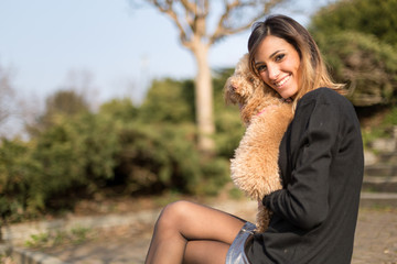 Beautiful young woman with her dog in a park
