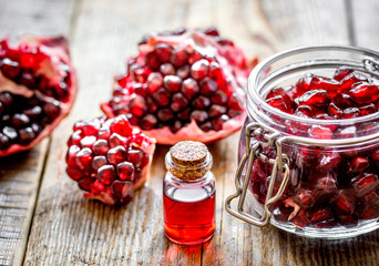 sliced pomegranate and extract in glass on wooden background