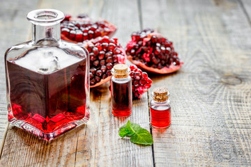 sliced pomegranate and extract in glass on wooden background