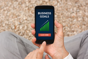 Hands holding smart phone with business goals concept on screen. All screen content is designed by me. Flat lay