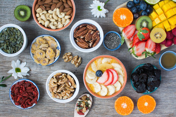 Smoothies made with satsumas, golden kiwis, mango and banana with fruits and berries on the wooden table, top view, selective focus