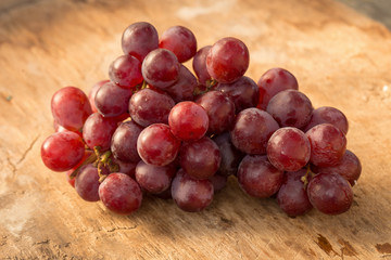 Bunches of fresh ripe red grapes on a wooden table.