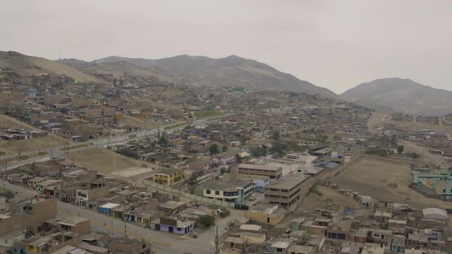 Ventanilla Peru Aerial v3 Flying low over urban poverty hillside housing area panning.