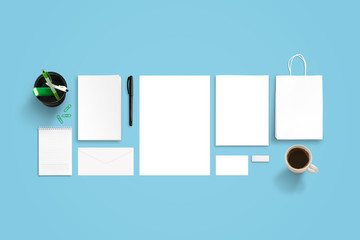 Branding stationery mockup on blue desk. Top view of paper, book, envelope, business card, bag, pad, pens and coffee.