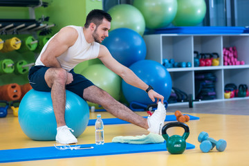 Fototapeta na wymiar Portrait of a fitness man doing stretching exercises at gym
