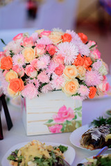 White box with pink and beige flowers stands on white dinner table