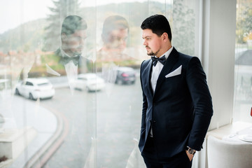 Thoughtful brunette man stands before panoramic window in restaurant hall