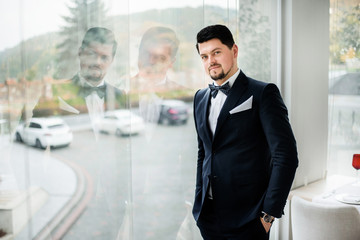 Fototapeta premium Thoughtful brunette man stands before panoramic window in restaurant hall