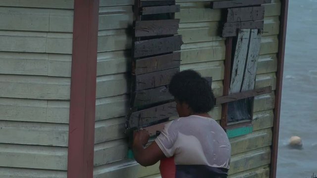 Fijian woman boarding up her house during a Tropical Cyclone