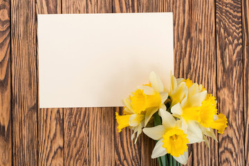 Fresh  spring yellow  daffodils  flowers and empty tag on brown painted wooden planks. Selective focus. Place for text.
