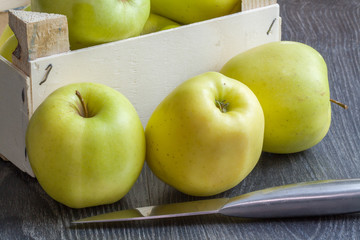 Pommes Golden devant  un cageot sur fond noir