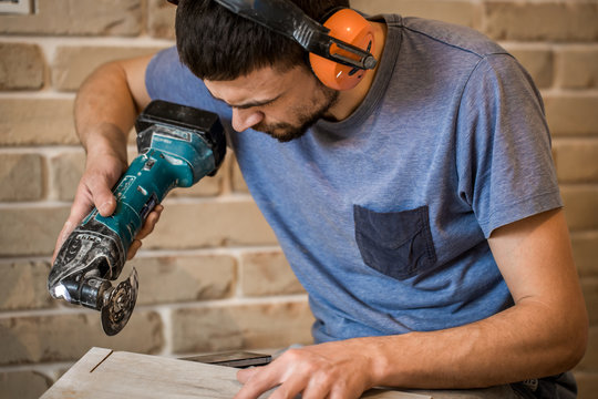 man in headphones works with manual electric saw