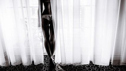 Woman in white lingerie poses between curtains