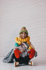 Beautiful girl sitting on the floor with knitted clothing