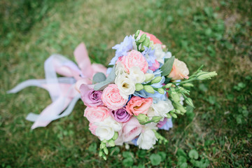 Wedding bouquet made of pink roses and green buds lies on the lawn