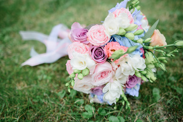 Wedding bouquet made of pink roses and green buds lies on the lawn
