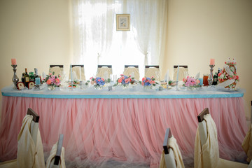 Dinner table for wedding couple decorated with blue and pink cloth waits for wedding couple