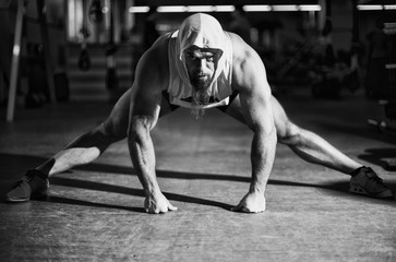Fototapeta premium Portrait of a fitness man doing stretching exercises at gym