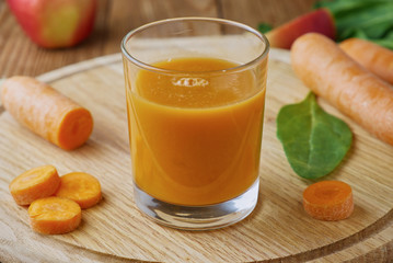 Fresh carrot juice in a glass on a wooden table