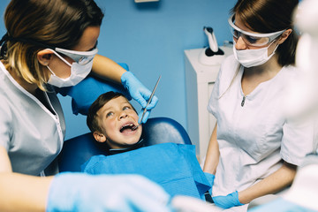 Dentists with a patient during a dental intervention to boy.