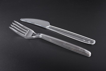 disposable plastic tableware. fork and knife on black background.