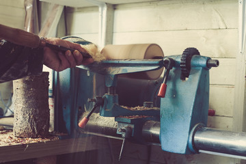 Man using old wood lathe turning wood, selective focus, dark toned photo