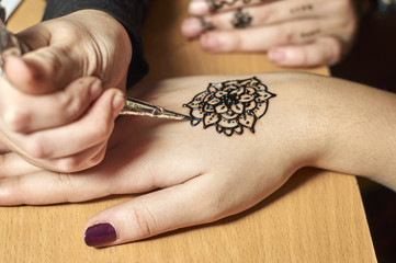 Girl drawing patterns by henna on the hands