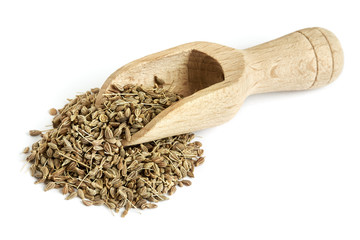 Pile of of dried anise seed (aniseed) with wooden scoop isolated on white background
