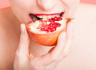 Woman mouth in closeup eating fresh pomegranate