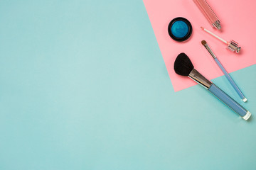 Colorful cosmetics on blue workplace with copy space. Cosmetics make up artist objects: lipstick, eye shadows, powder, tools for make-up.Top view.