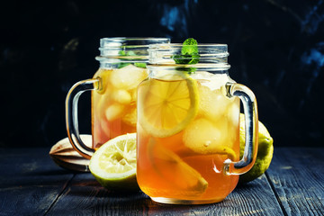 Black ice tea with lemon in a glass jar on a dark background, selective focus