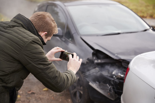 Man Taking Photo Of Car Accident On Mobile Phone