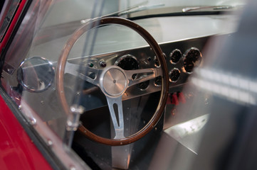 Classic car steering wheel and dashboard with many gauges. Classic race car interior.