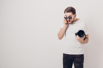 young professional photographer in white shirt holds digital cam